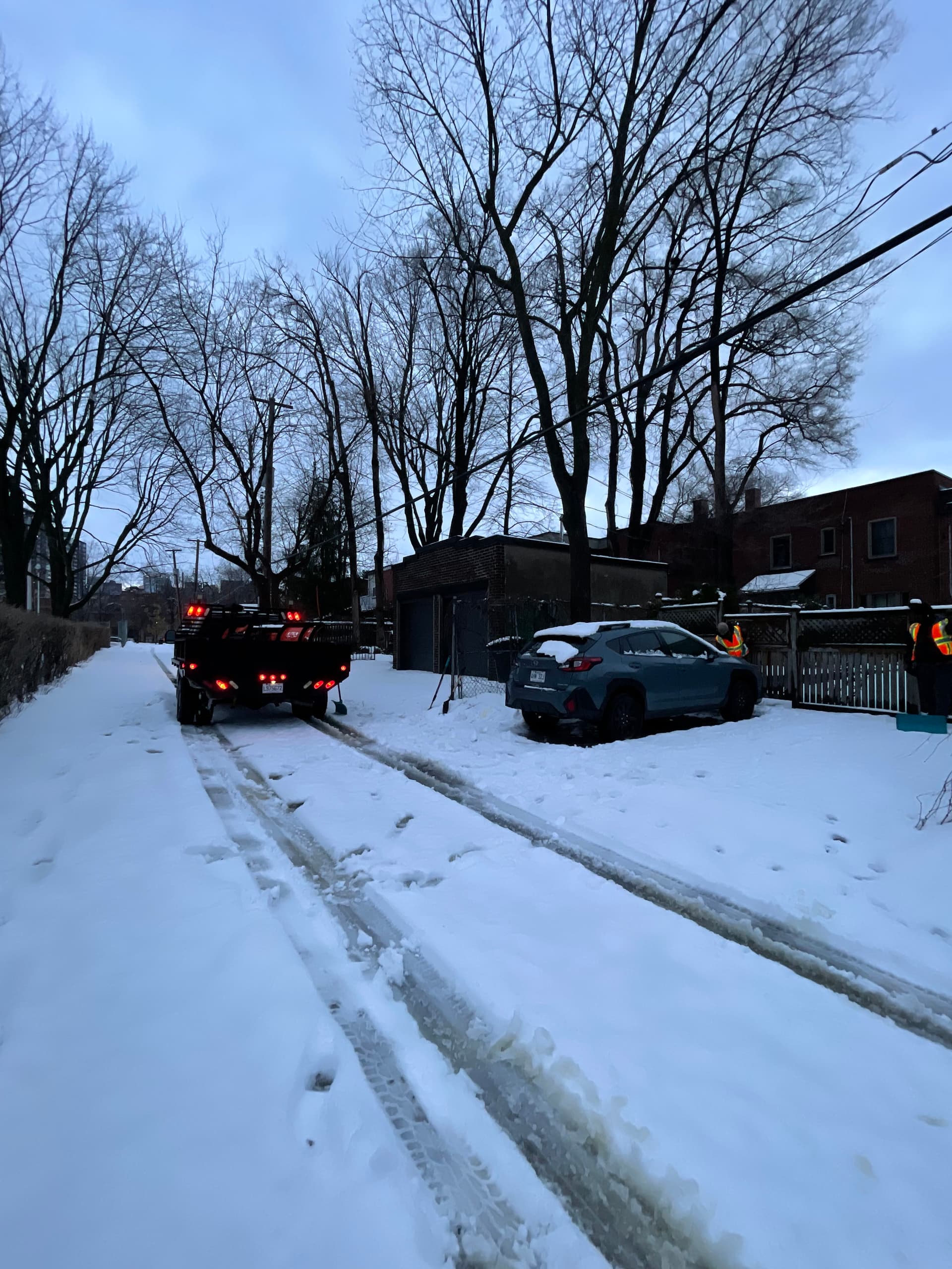 Snoen crew member shoveling snow from a residential driveway at night